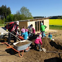 Gemeinsam wird der große Erdhaufen eingeschaufelt und verteilt.